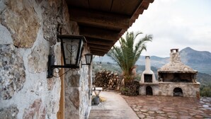 Edifici rústic de pedra amb teulada de fusta, xemeneu de pedra i forn de pedra.
