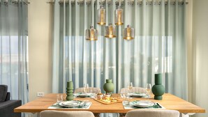 Un comedor con una mesa de madera dispuesta para dos personas, rodeada de sillas de colores claros.