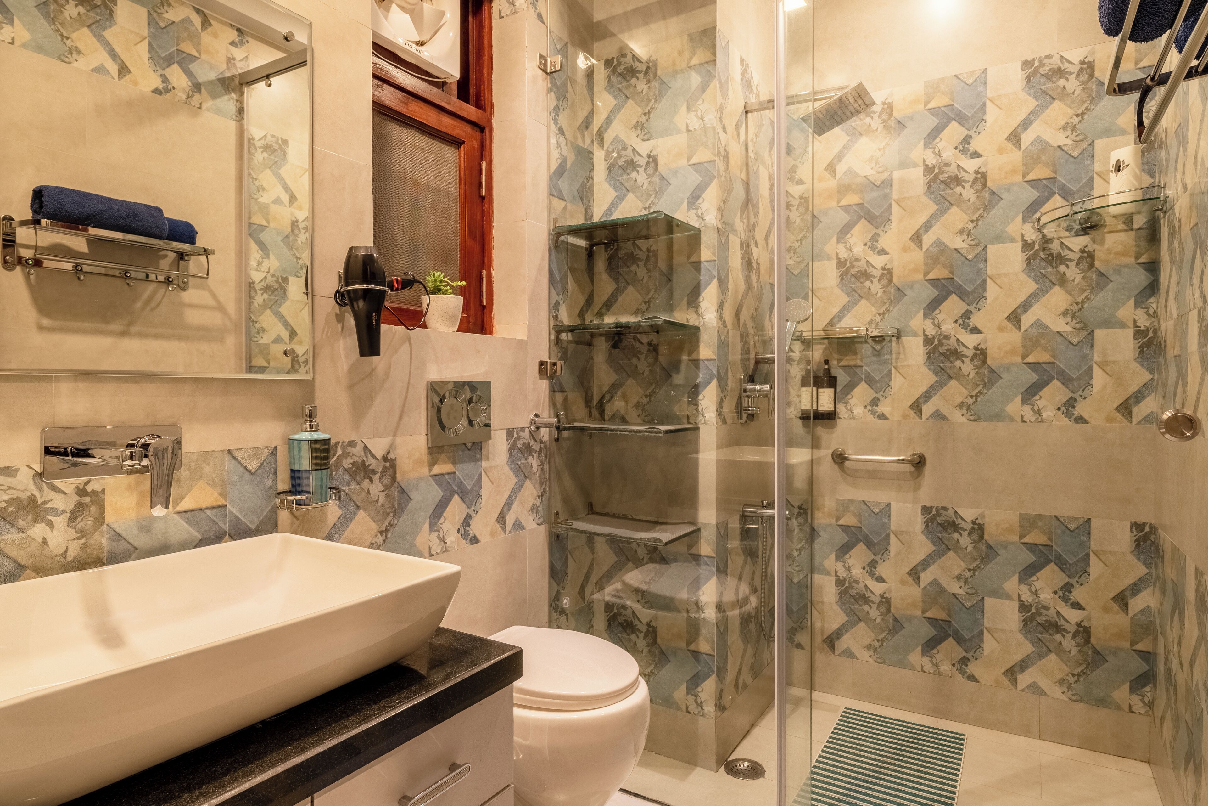 A modern bathroom with a large sink, toilet, and glass-enclosed shower.