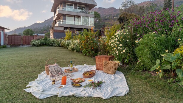 A picnic setup on a grassy lawn with a house in the background. - Celestial Rhapsody (Nainital)