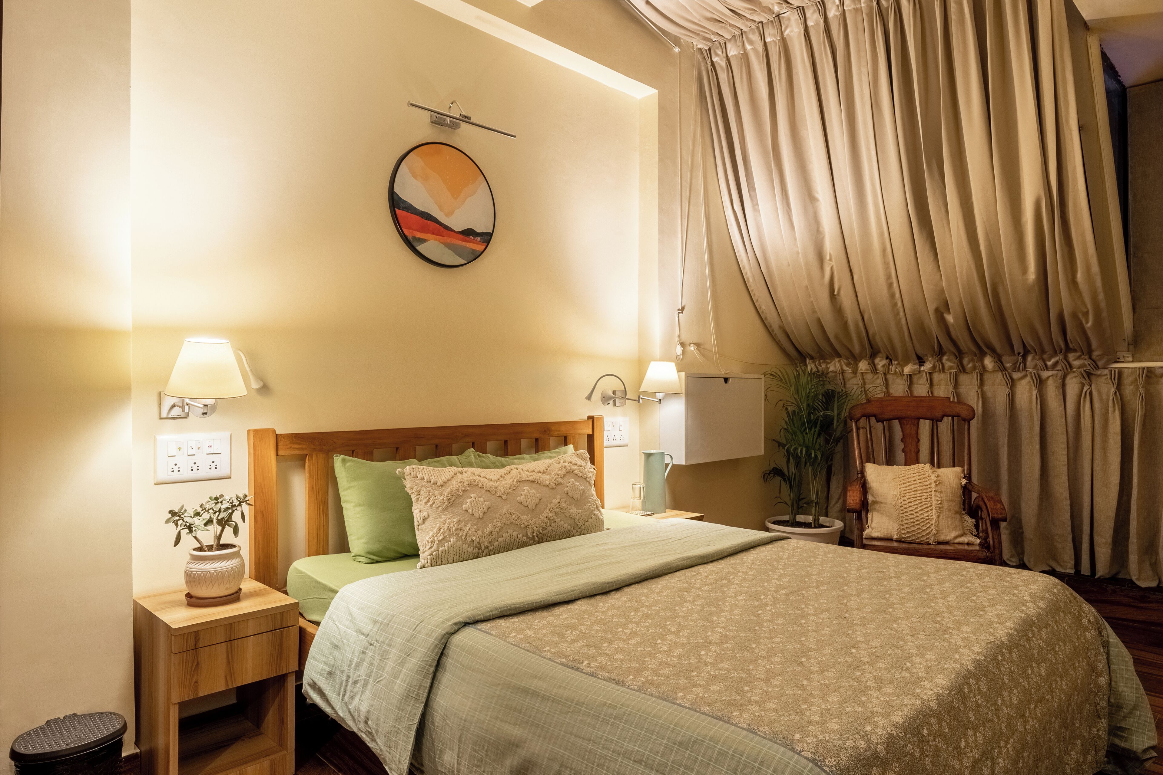 A neatly arranged bedroom with a bed, bedside tables, a lamp, a chair, and a wall-mounted artwork.