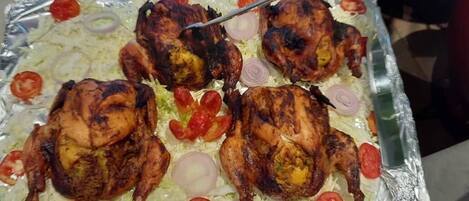 A tray of grilled chicken with tomatoes and onions.