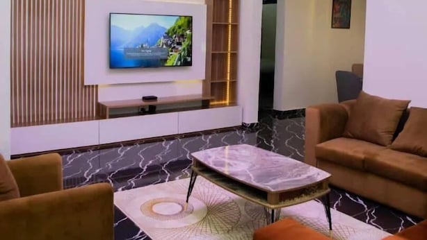 Ein modernes Wohnzimmer mit Flachbildfernseher, einer Kristallleuchtre und einem Sofa.