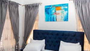 Ein Schlafzimmer mit einem großen Bett, grauen Vorhängen und einem blauen Kopfteil.