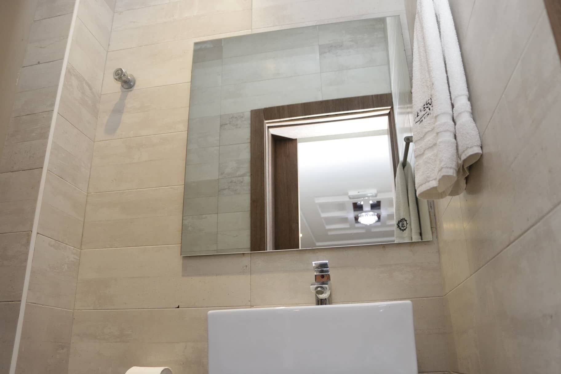 Une salle de bain avec un grand miroir, un lavabo et une serviette accrochée au mur.