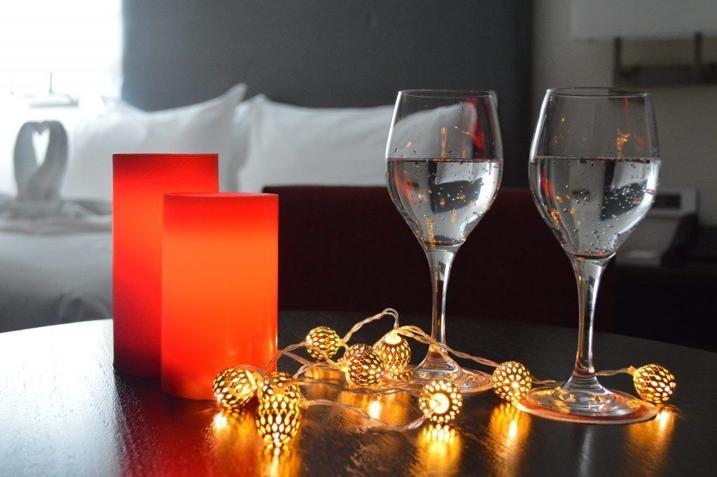 Two glasses of water on a table with decorative lights and a red candle.
