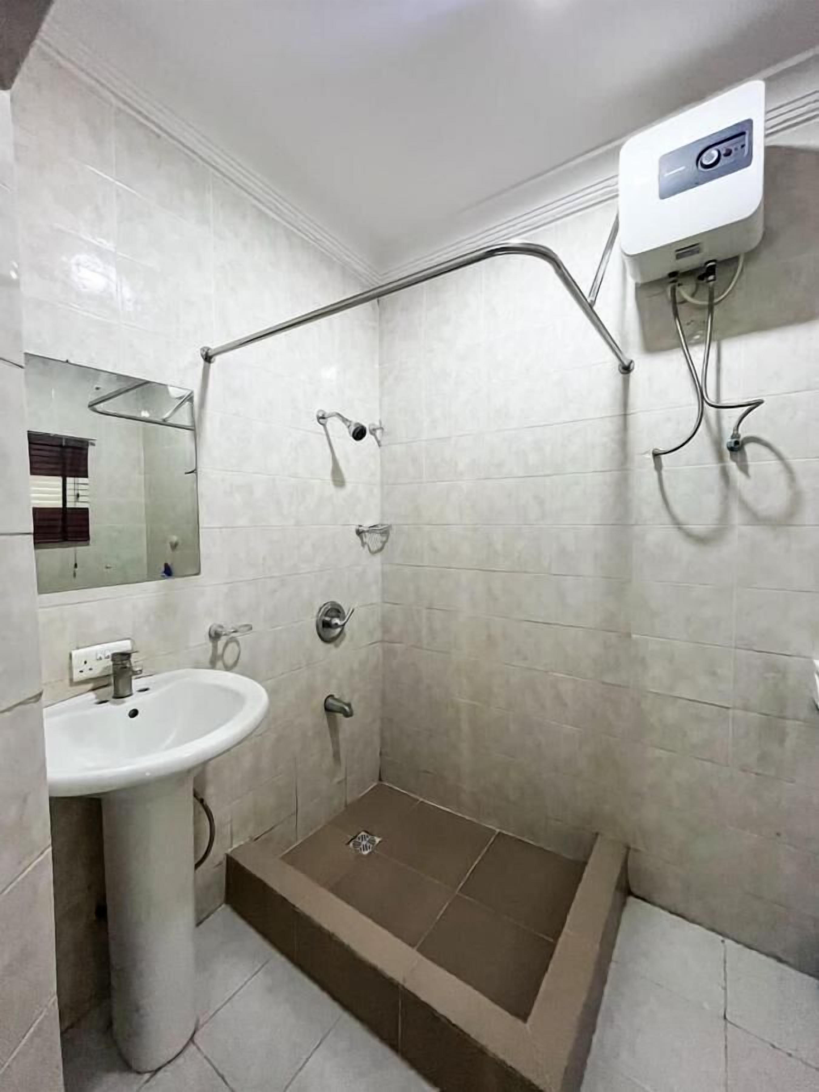 Un baño con ducha, lavamanos y espejo.