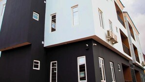 A multi-story residential building with a modern design, featuring a combination of dark and light facades, multiple windows, and balconies. - Delight Hotel and Suites Ado Ekiti (Ado Ekiti)