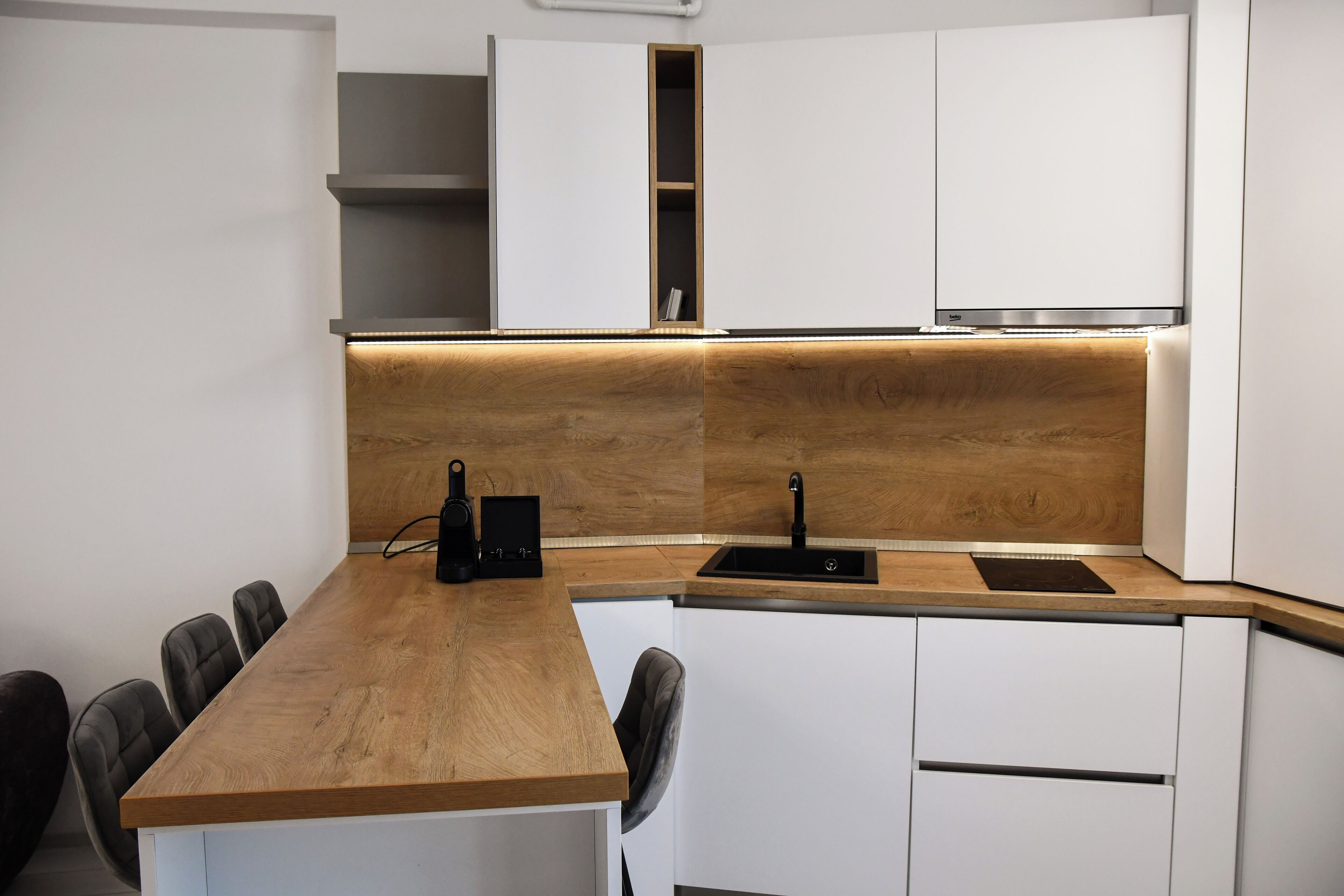 A modern kitchen with a wooden countertop, white cabinets, and a built-in sink.