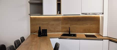 A modern kitchen with a wooden countertop, white cabinets, and a built-in sink.