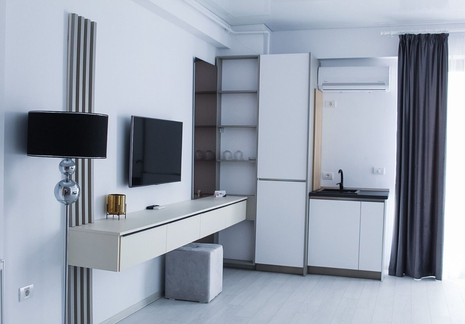 A modern kitchen with a built-in oven, a flat-screen TV, and a small dining area.