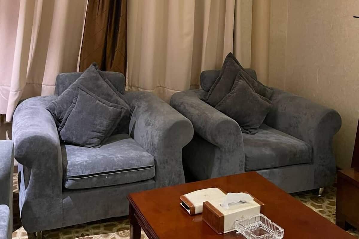 A room with two grey sofas, a wooden coffee table, and a large window with curtains.