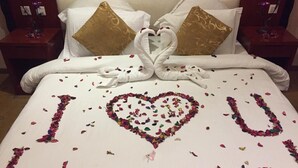 Een bed met een hartvormige bloemstuk van rozenblaadjes, waarop ‘Ik hou van jou’ staat.