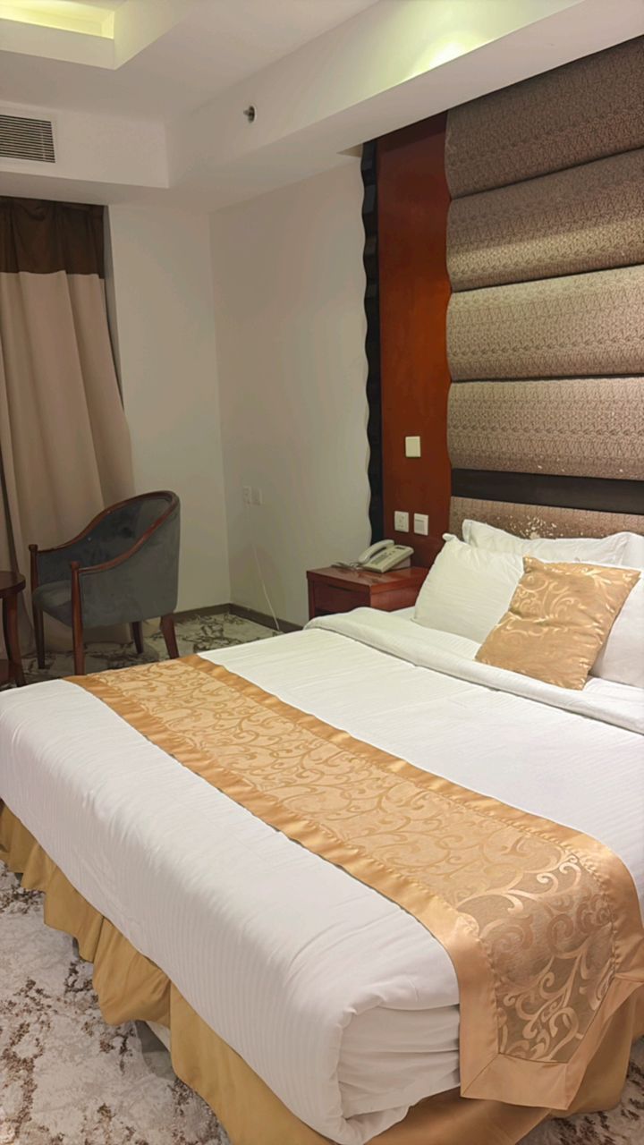 Una habitación de hotel con una cama grande, una silla, una mesita de noche y un teléfono.