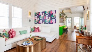 A modern living room with a white sofa, colorful cushions, a coffee table, and a vibrant pop art wall. - Casa Zoë | Royal House – Charleston’s Crown (Charleston)