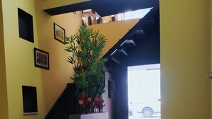 Een kamer met een bank, een tafel, een potplant en een trap naar een balkon.