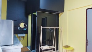 Een kleine kamer met een bed, een tafeltje, een kledingrek en een deur.