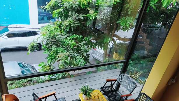 Een balkon met buitenmeubilair, uitzicht op een straat en een boom.