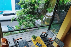 A balcony with outdoor seating, a view of a street, and a tree. - Shusimi Boutique (Ho Chi Minh City)
