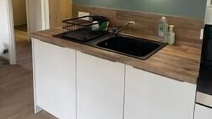 Eine Küche mit weißen Schränken, einer Holzausziehtafel und einem Spülbecken.