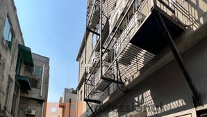 Un callejón estrecho con un edificio que tiene una escalera de incendios y una puerta de garaje.