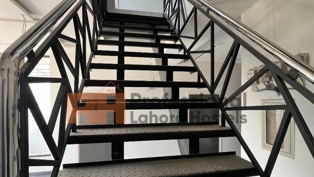 Una escalera con barandillas de metal y peldaños con textura que conduce a un piso superior.
