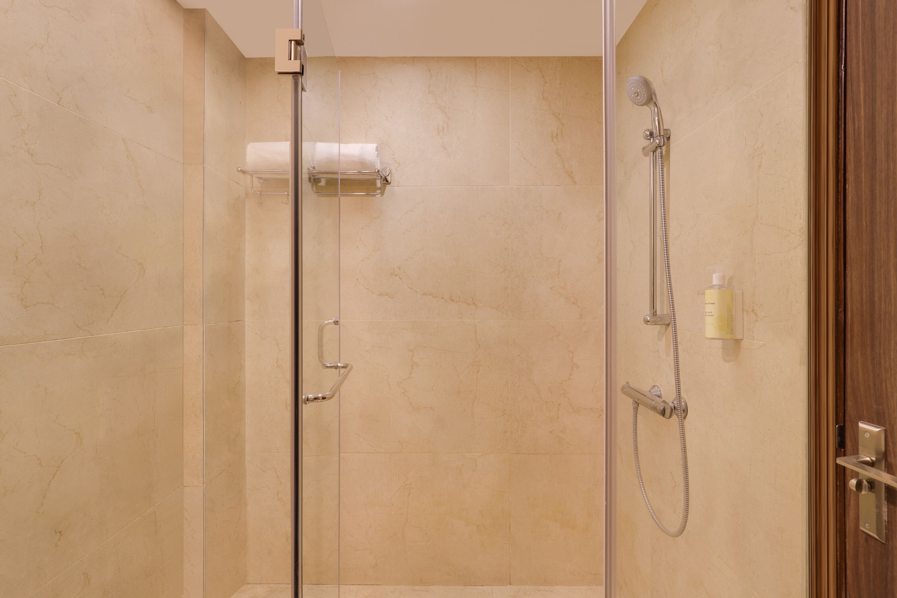 A modern bathroom with a glass shower enclosure, a towel rack, and a handheld showerhead.