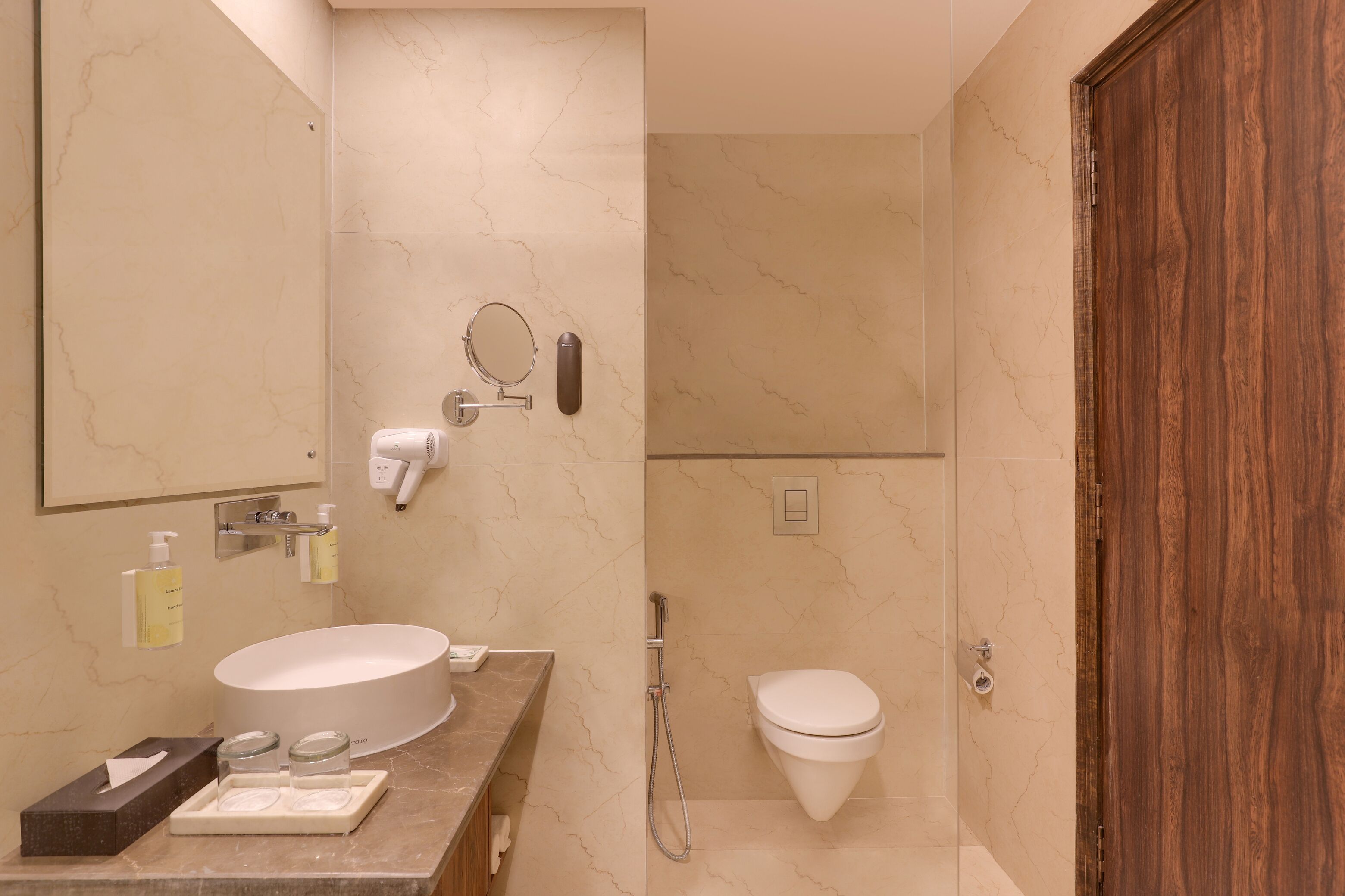 A modern bathroom with a round sink, a toilet, and a shower.