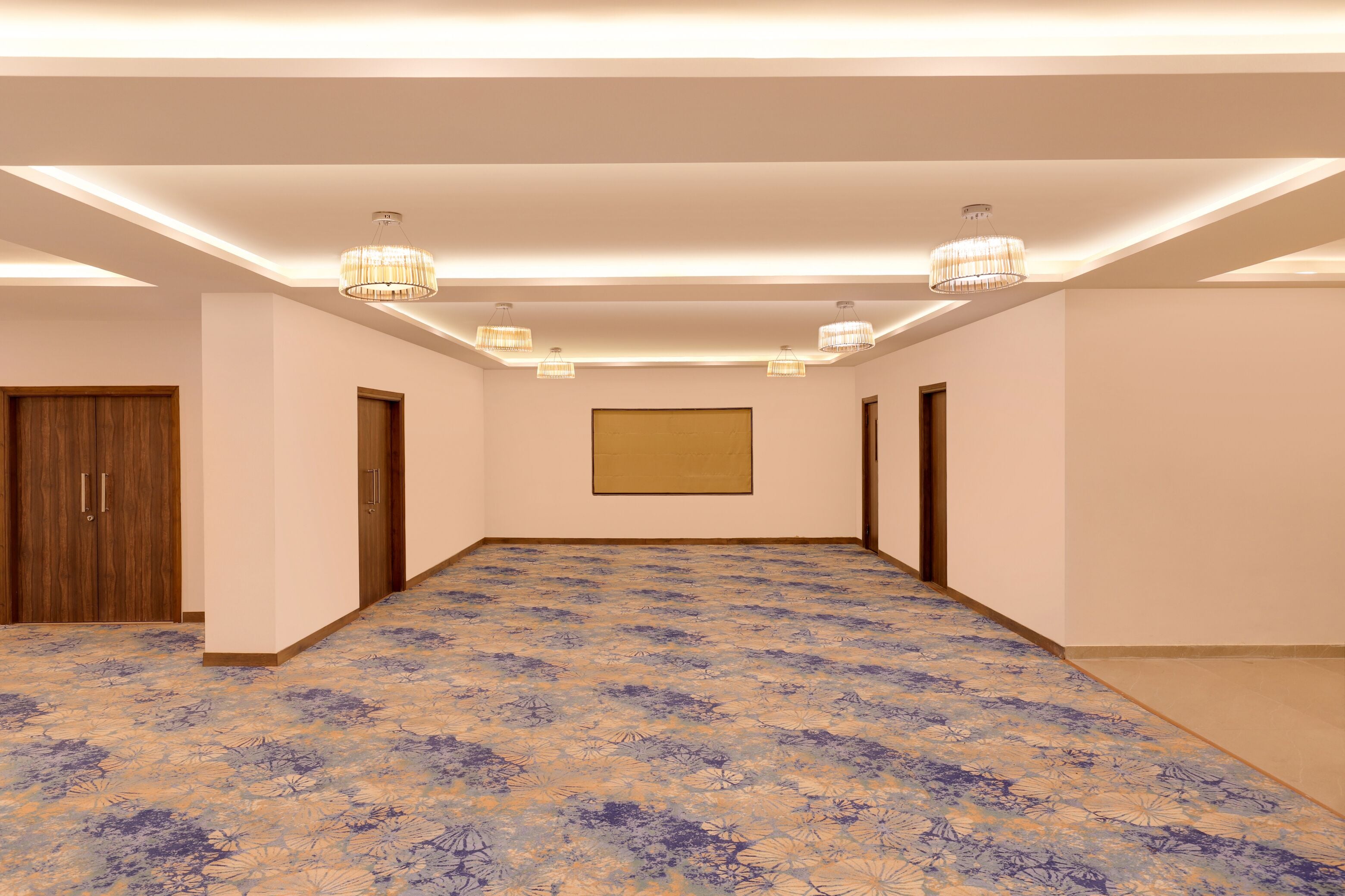 A spacious room with a patterned floor, recessed lighting, and wooden doors.