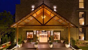 L’entrée d’un hôtel, avec une façade en briques, un pignon en bois et un lustre central.