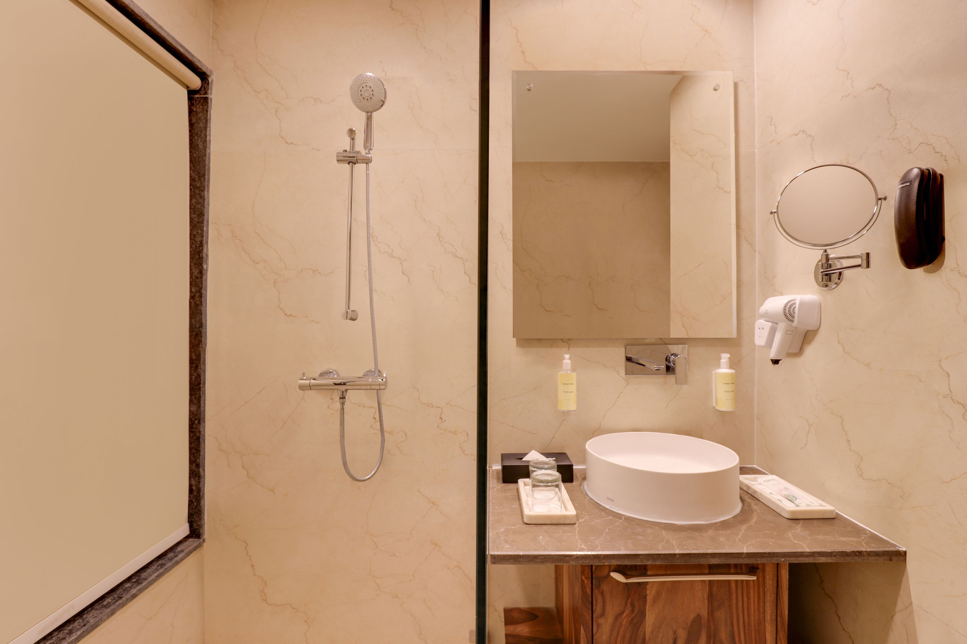 A bathroom with a shower, sink, mirror, and toiletries.