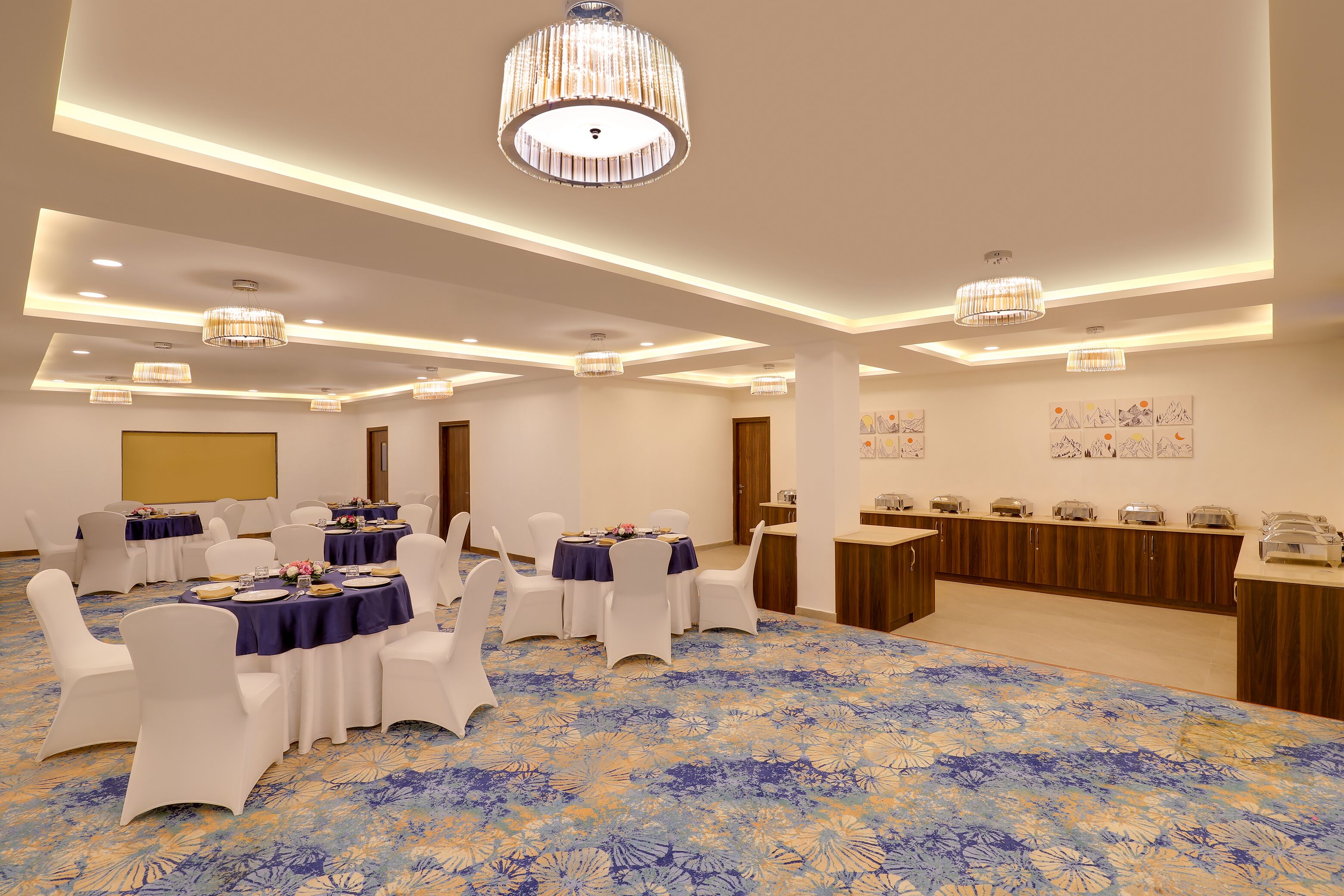 A conference room with round tables, white chairs, and a buffet setup.