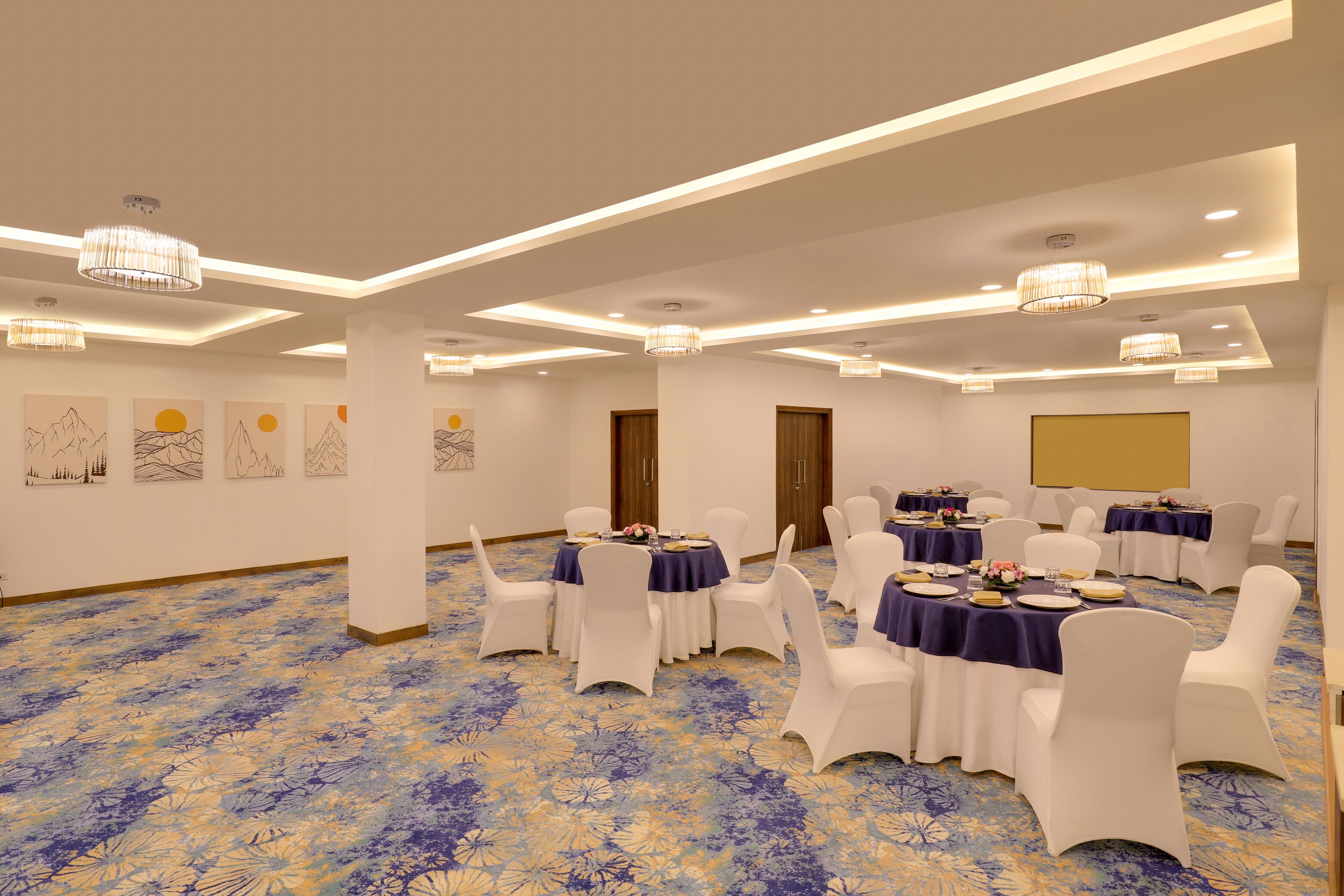 A conference room with round tables, white chairs, and a patterned carpet.