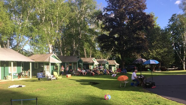 Ein Campingplatz mit grünen Hütten, einer Rasenfläche und einem Spielplatz.