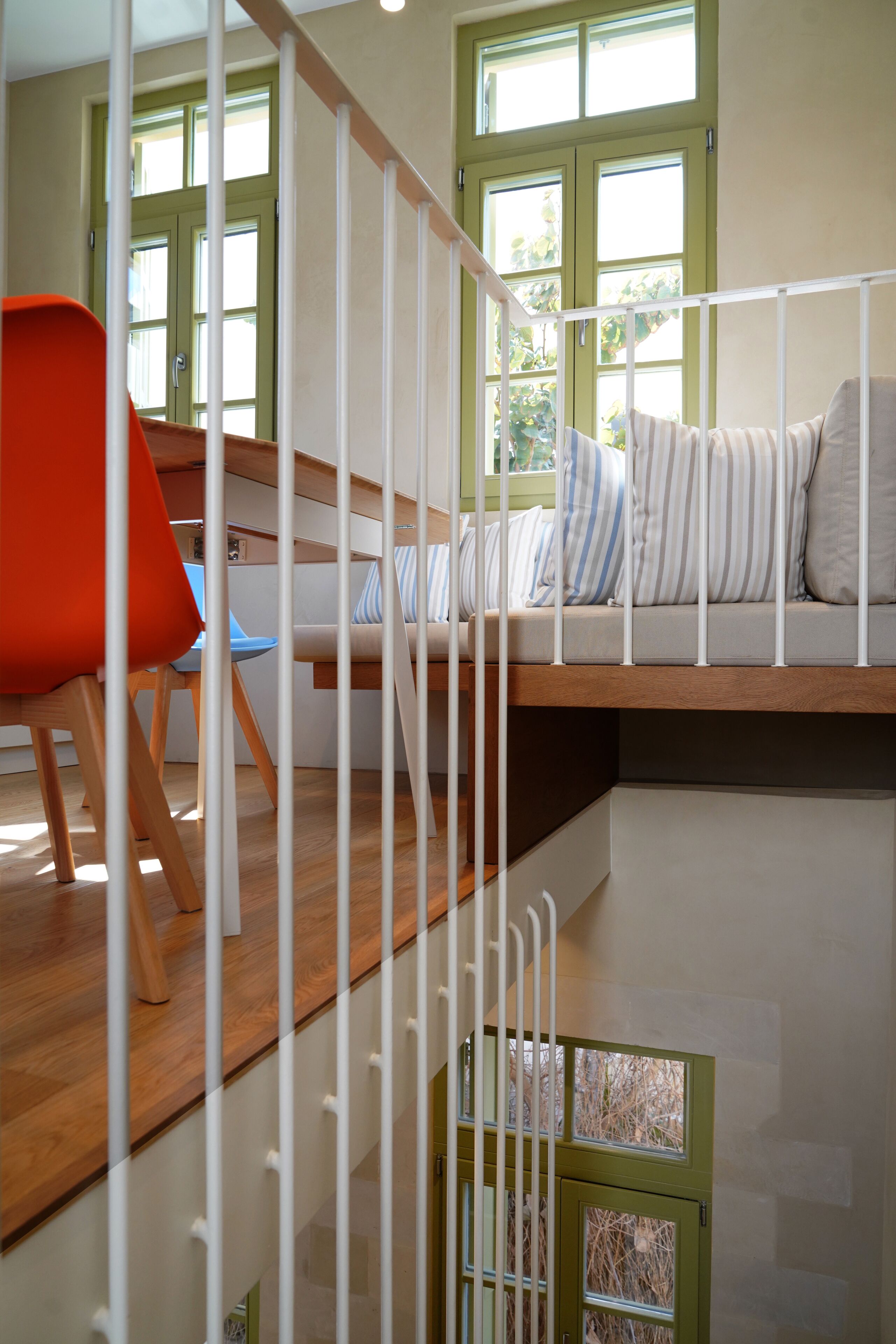 A staircase with a wooden finish, a white railing, and a view of a room with a sofa and a chair.
