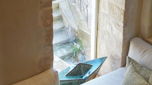 A cozy room with a stone wall, a cushioned sofa, and a small table with a decorative item.