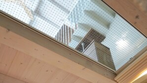 A modern interior with a wooden ceiling, a staircase with white steps, and a green door.