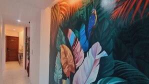 Un couloir orné d’une fresque colorée représentant des feuilles tropicales et un perroquet.