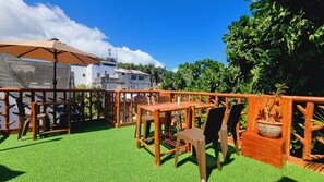 An outdoor patio with a wooden table and chairs, surrounded by a wooden fence and greenery. - CiNta Hotel (Boracay Island)