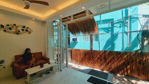 Un salon moderne avec un canapé, une table basse et une grande fenêtre donnant sur un immeuble bleu et une clôture en bois.