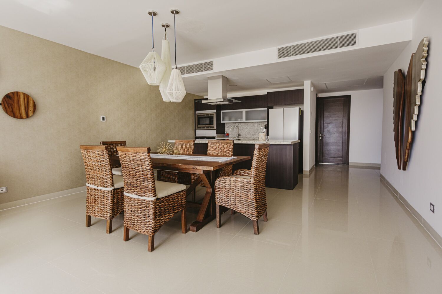 A modern kitchen with dark cabinets, a central island, and a built-in oven.