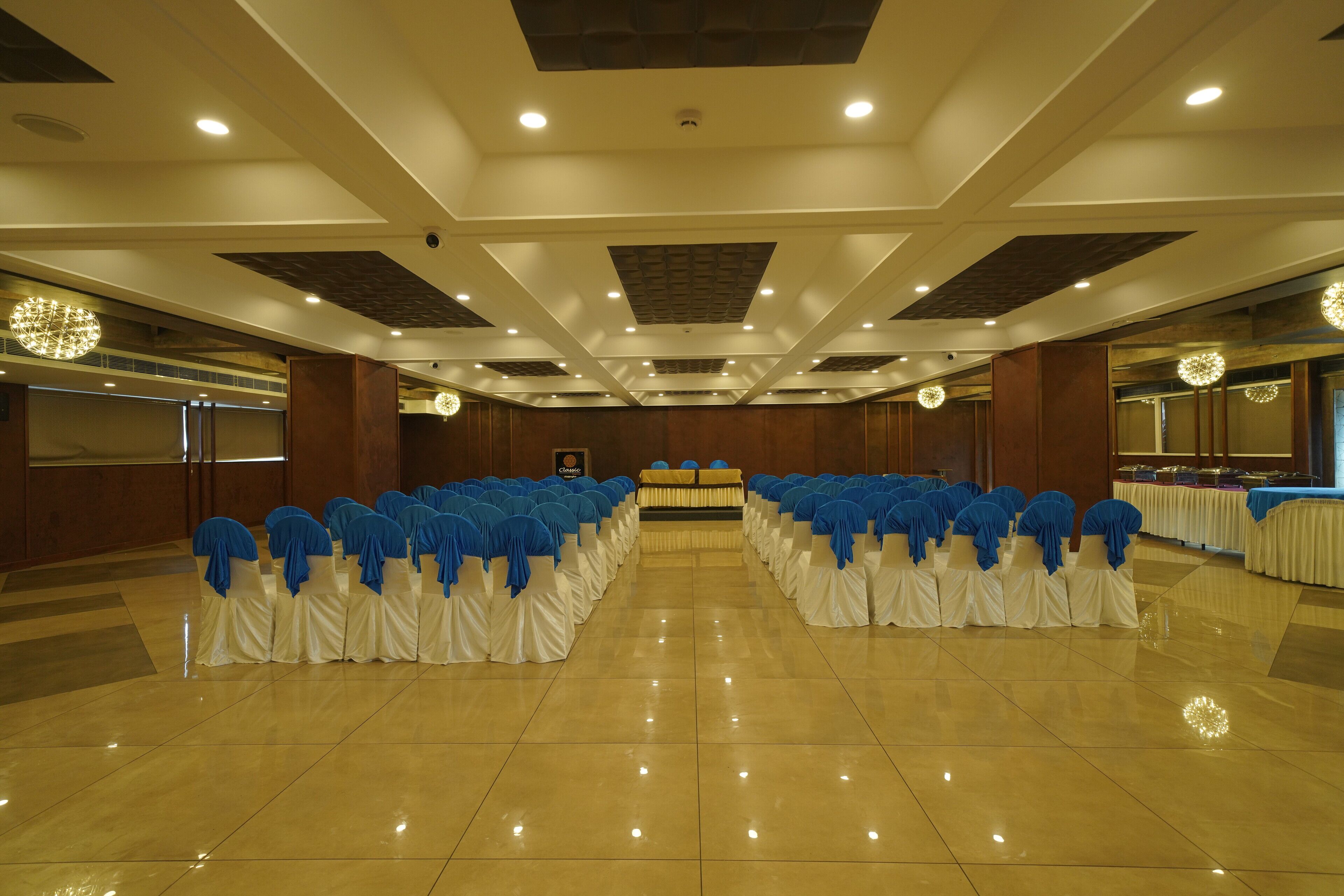 A banquet hall with rows of tables, white tablecloths, and blue chair covers.
