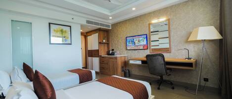 A hotel room with two beds, a desk, a chair, a lamp, and a TV.