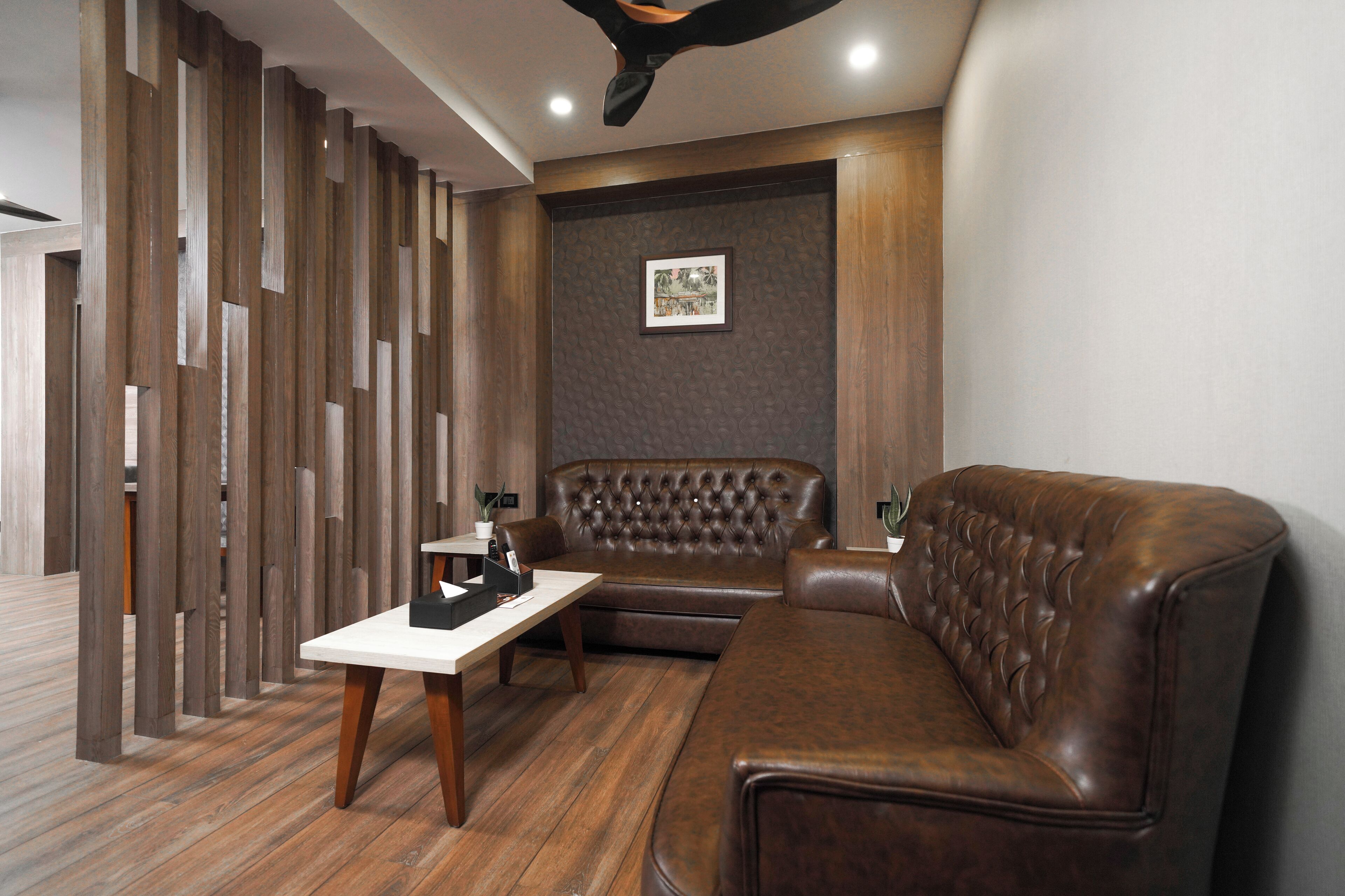 Un moderno salón con un sofá de cuero marrón, una mesa de centro blanca y una pared con diseño en tonos marrones.