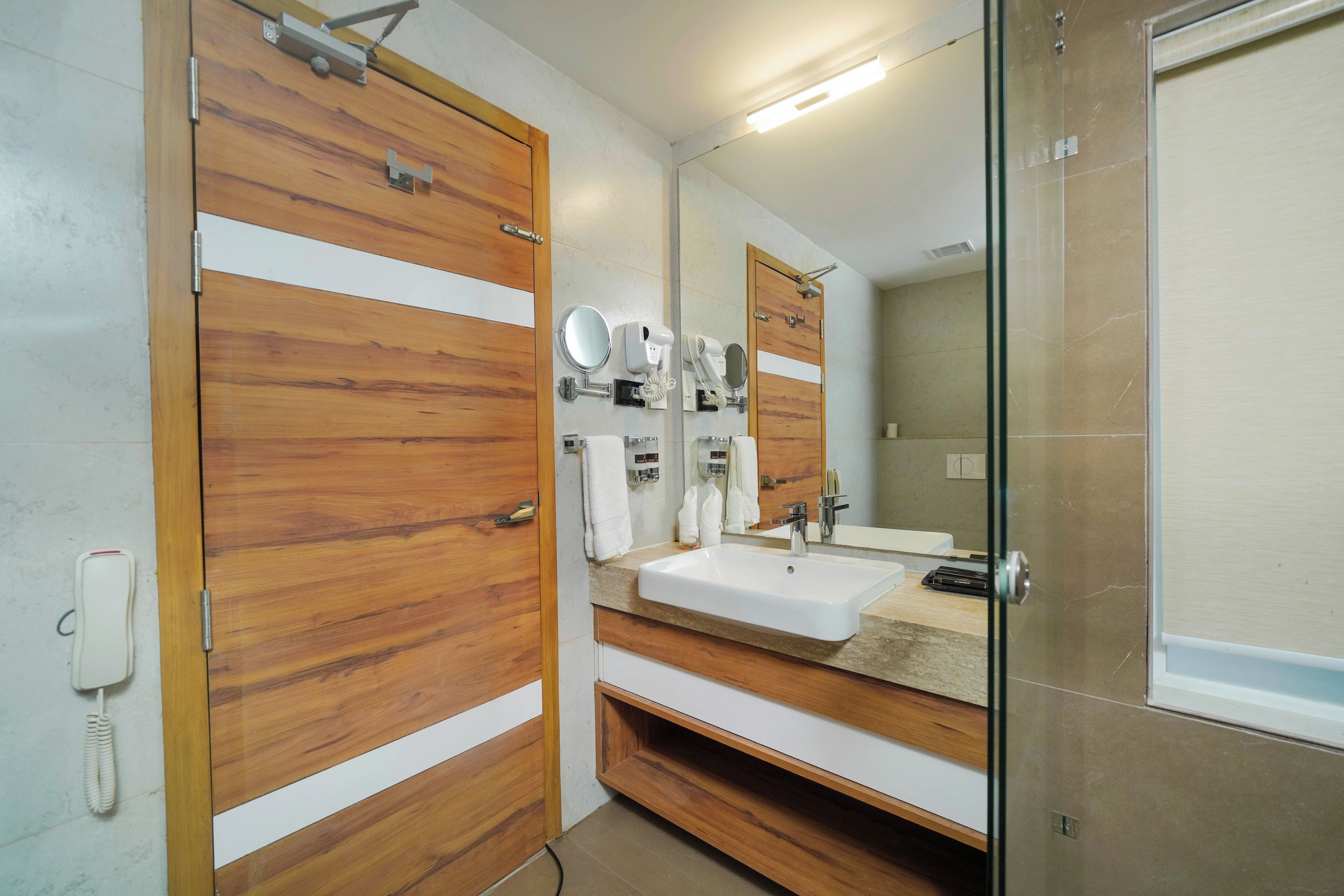 A bathroom with wooden doors, a sink, a mirror, and a phone.