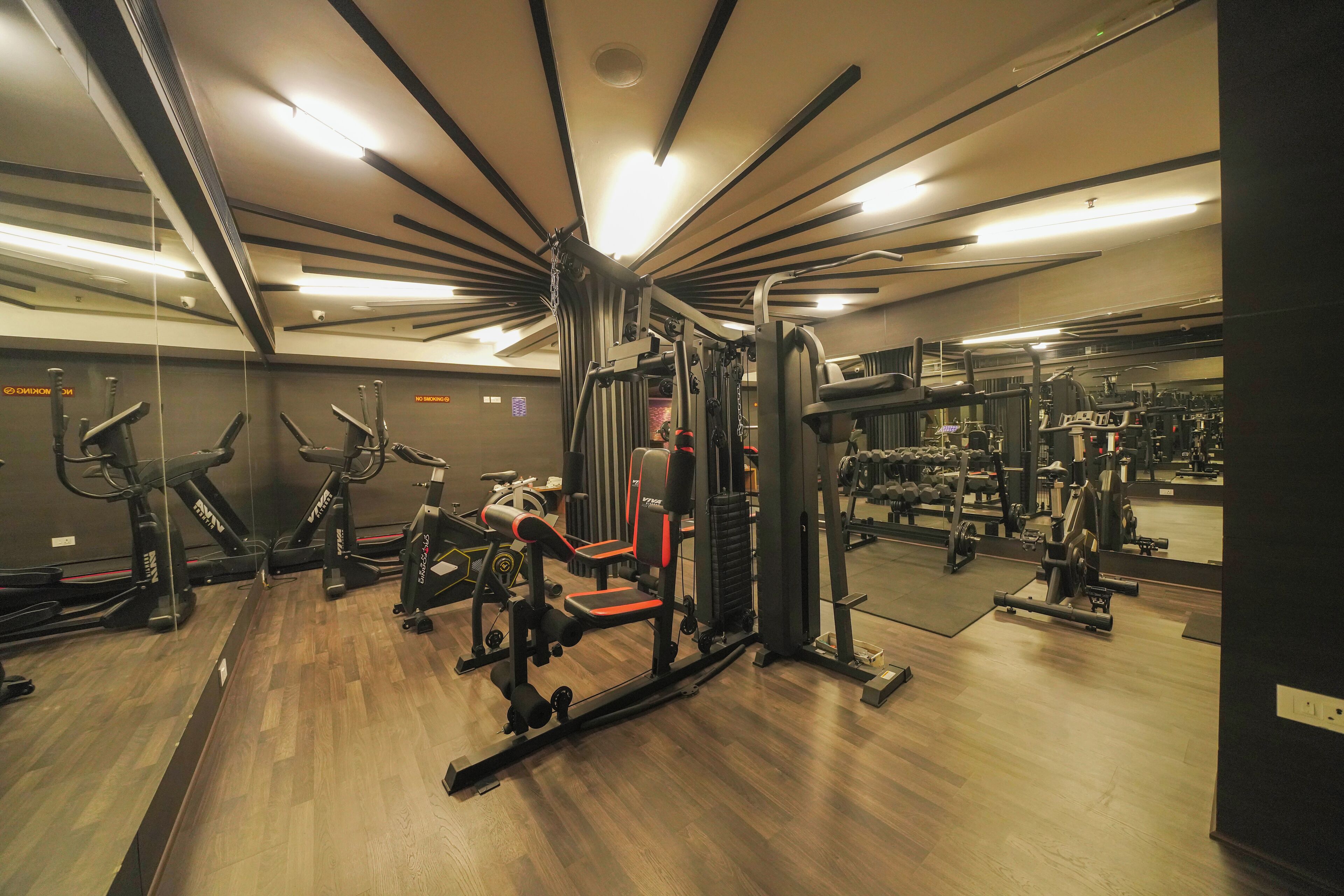 A gym with cardio machines, weightlifting equipment, and mirrors on the walls.