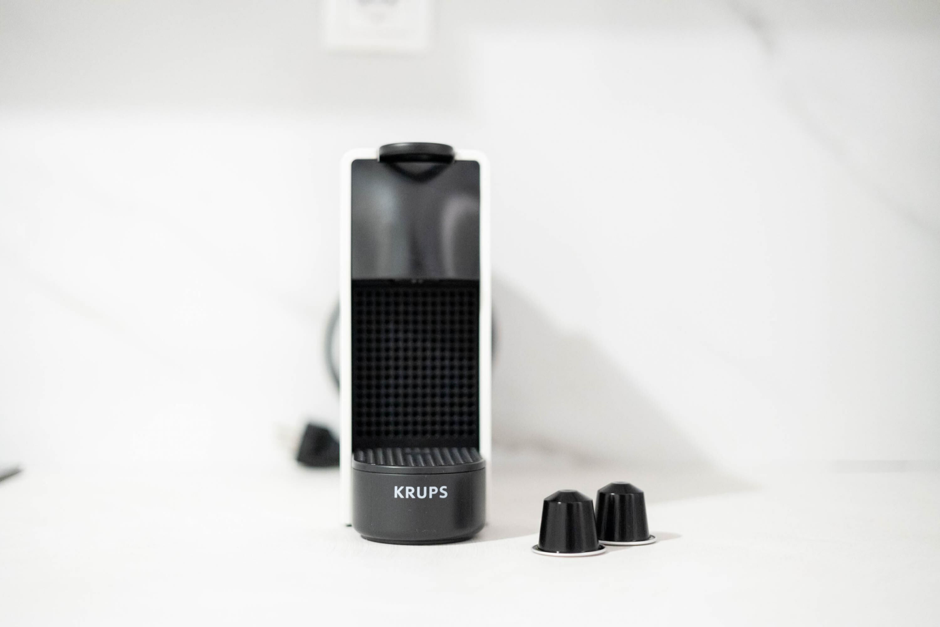 A black speaker with the brand name 'KRUPS' and two black knobs on a white surface.