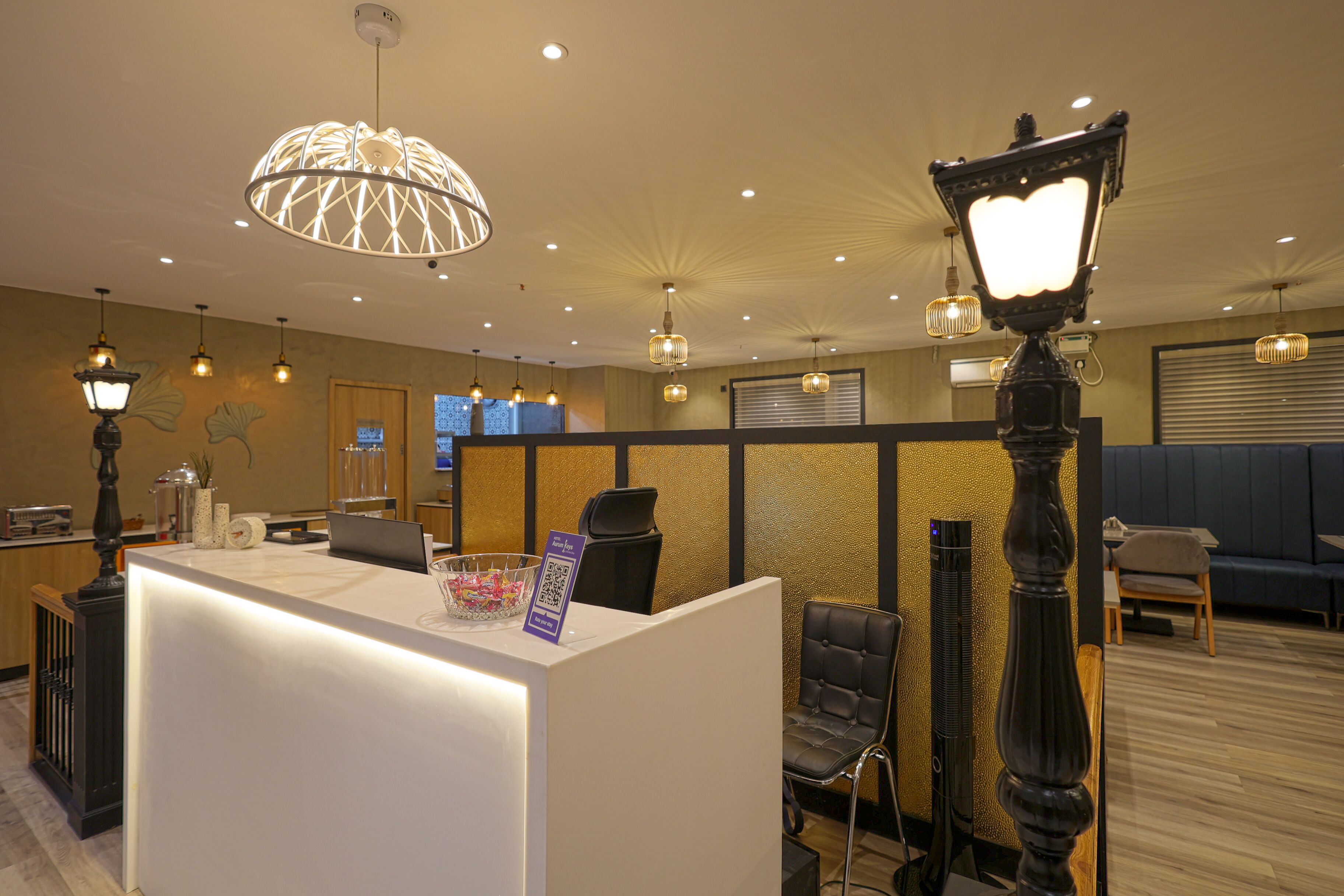 A hotel reception area with a modern design, featuring a reception desk, seating area, and decorative lighting.