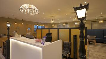 A hotel reception area with a modern design, featuring a reception desk, seating area, and decorative lighting.