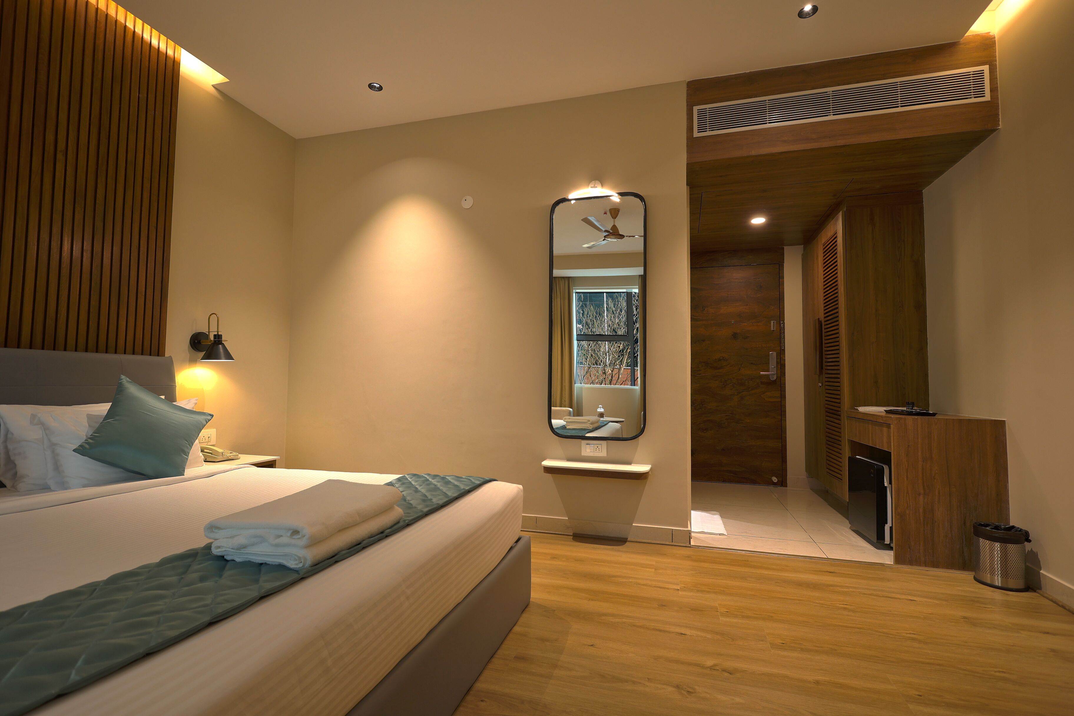 A modern bedroom with a large bed, bedside lamp, and a mirror.